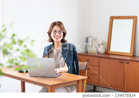 在客廳裡使用電腦的中年女人 在客廳裡使用電腦的中年女人 139078924