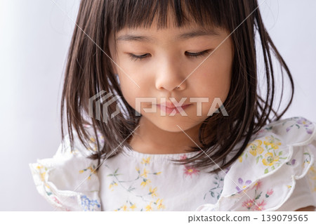 A young girl with her head bowed 139079565