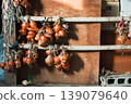 Onions drying on a pole in front of a wooden wall 139079640