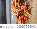 A bundle of red chili peppers hanging under the eaves to dry. 139079641