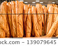 A large number of baguettes displayed upright on a metal rack. 139079645
