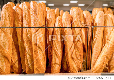 A large number of baguettes displayed upright on a metal rack. A large number of baguettes displayed upright on a metal rack. 139079645