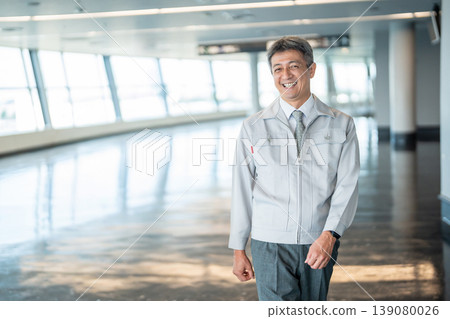 A man in work clothes standing in an office corridor A man in work clothes standing in an office corridor 139080026