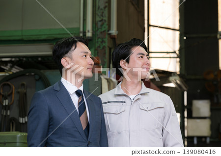 A portrait of factory workers and businessmen working together, looking up at the future and hope; men in suits and work clothes. A portrait of factory workers and businessmen working together, looking up at the future and hope; men in suits and work clothes. 139080416