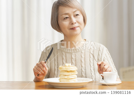 Senior woman eating pancakes in the dining room Senior woman eating pancakes in the dining room 139081116