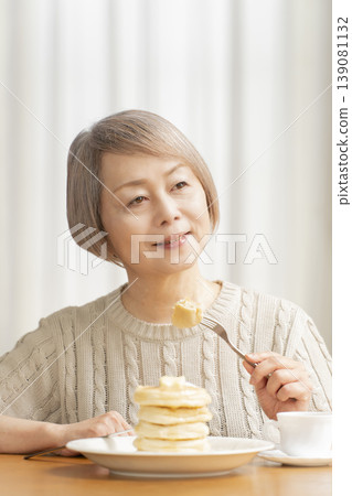Senior woman eating pancakes in the dining room Senior woman eating pancakes in the dining room 139081132