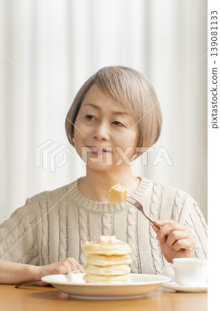 Senior woman eating pancakes in the dining room Senior woman eating pancakes in the dining room 139081133