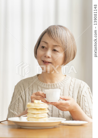 Senior woman eating pancakes in the dining room Senior woman eating pancakes in the dining room 139081148