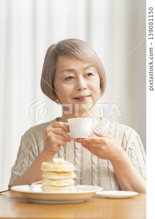 Senior woman eating pancakes in the dining room Senior woman eating pancakes in the dining room 139081150