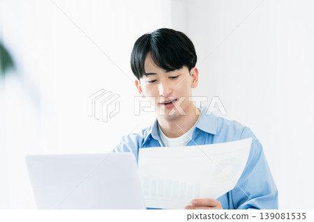 A young man thinking while looking at documents. A young man thinking while looking at documents. 139081535