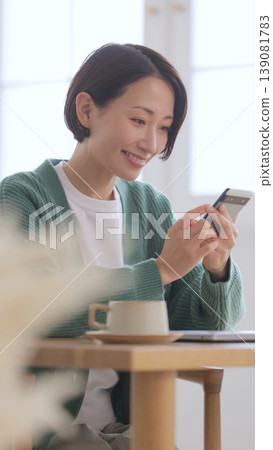 一個女人在一家咖啡館看智能手機 一個女人在一家咖啡館看智能手機 139081783