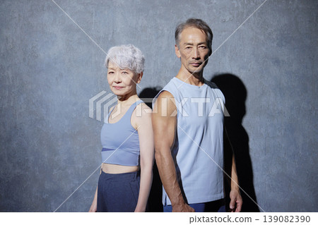 一位老年男性和一位老年女性在黑色背景下鍛煉，直視鏡頭。 139082390