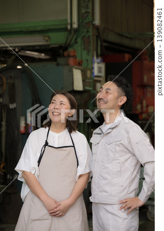 The smiles of a couple working in a small factory in the manufacturing industry, looking up at the future and hope: Family businesses and manufacturing in small and medium-sized enterprises. The smiles of a couple working in a small factory in the manufacturing industry, looking up at the future and hope: Family businesses and manufacturing in small and medium-sized enterprises. 139082461