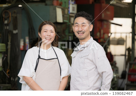 Smiling portraits of a couple working in a small factory, looking directly at the camera. Images of family-run businesses in small and medium-sized enterprises, manufacturing sites, and chambers of commerce. Smiling portraits of a couple working in a small factory, looking directly at the camera. Images of family-run businesses in small and medium-sized enterprises, manufacturing sites, and chambers of commerce. 139082467