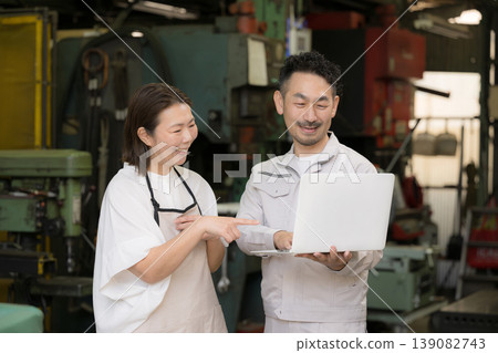 A couple using digital transformation (DX) to check laptops in a factory, showcasing a positive image of growth and success through IT and AI-driven business efficiency. A couple using digital transformation (DX) to check laptops in a factory, showcasing a positive image of growth and success through IT and AI-driven business efficiency. 139082743