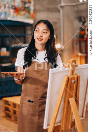 Female artist wears black hat posing near picture indoor the studio Female artist wears black hat posing near picture indoor the studio 139082835
