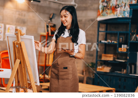Female artist wears black hat posing near picture indoor the studio Female artist wears black hat posing near picture indoor the studio 139082836