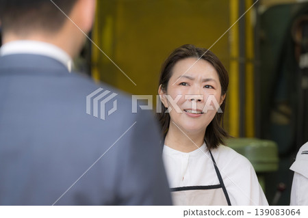 一位女工在小型工廠裡接待訪客——這是小鎮上的一幕商業景象。這是推銷電話嗎?她忙得不可開交… 一位女工在小型工廠裡接待訪客——這是小鎮上的一幕商業景象。這是推銷電話嗎?她忙得不可開交… 139083064