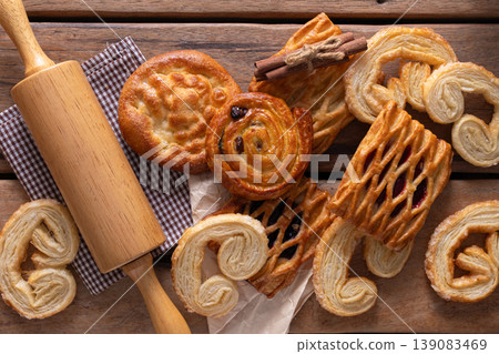 Freshly baked assorted pastries with a rolling pin on a rustic wooden table. 139083469