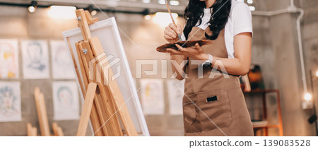 Female artist wears black hat posing near picture indoor the studio Female artist wears black hat posing near picture indoor the studio 139083528