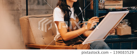 Female artist wears black hat posing near picture indoor the studio 139083529