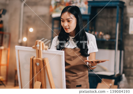 Female artist wears black hat posing near picture indoor the studio Female artist wears black hat posing near picture indoor the studio 139084193