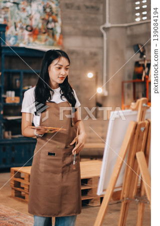 Female artist wears black hat posing near picture indoor the studio Female artist wears black hat posing near picture indoor the studio 139084194
