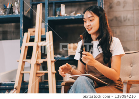Female artist wears black hat posing near picture indoor the studio Female artist wears black hat posing near picture indoor the studio 139084210