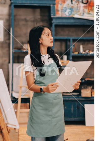 Female artist wears black hat posing near picture indoor the studio Female artist wears black hat posing near picture indoor the studio 139084223