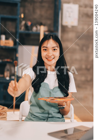 Female artist wears black hat posing near picture indoor the studio Female artist wears black hat posing near picture indoor the studio 139084240