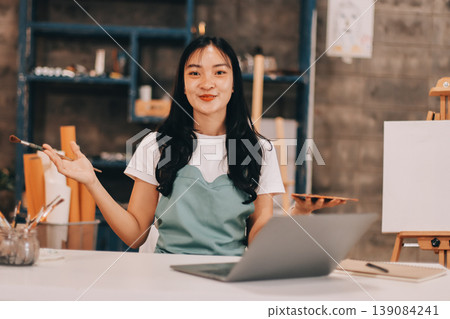 Female artist wears black hat posing near picture indoor the studio Female artist wears black hat posing near picture indoor the studio 139084241