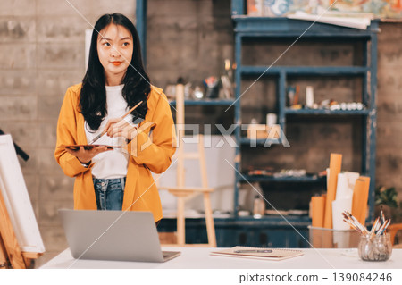 Female artist wears black hat posing near picture indoor the studio Female artist wears black hat posing near picture indoor the studio 139084246