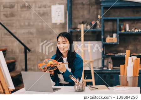 Female artist wears black hat posing near picture indoor the studio Female artist wears black hat posing near picture indoor the studio 139084250