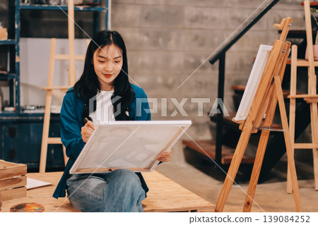 Female artist wears black hat posing near picture indoor the studio Female artist wears black hat posing near picture indoor the studio 139084252