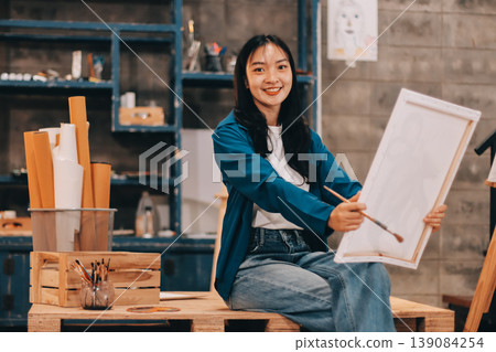 Female artist wears black hat posing near picture indoor the studio Female artist wears black hat posing near picture indoor the studio 139084254
