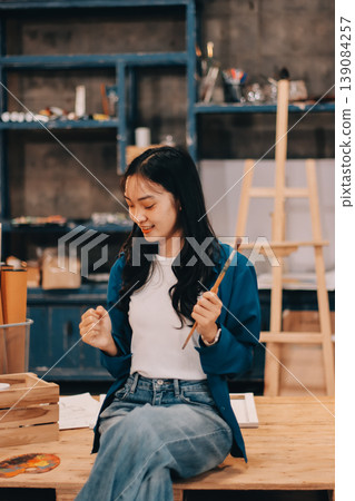 Female artist wears black hat posing near picture indoor the studio Female artist wears black hat posing near picture indoor the studio 139084257