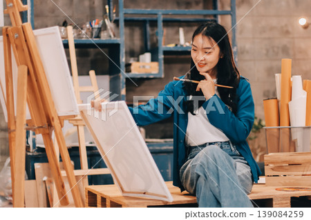 Female artist wears black hat posing near picture indoor the studio 139084259