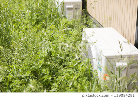 Air conditioner outdoor unit covered in weeds Air conditioner outdoor unit covered in weeds 139084291