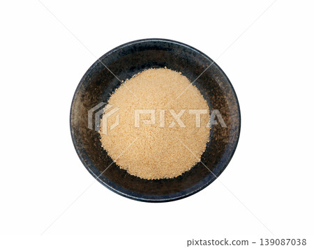Powdered brown sugar served on a black plate [White background, cutout] 139087038