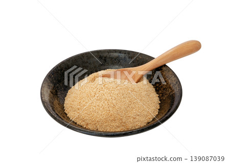 Powdered brown sugar served on a black plate [White background, cutout] 139087039