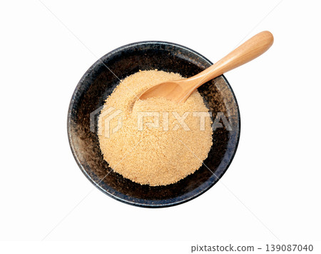 Powdered brown sugar served on a black plate [White background, cutout] 139087040