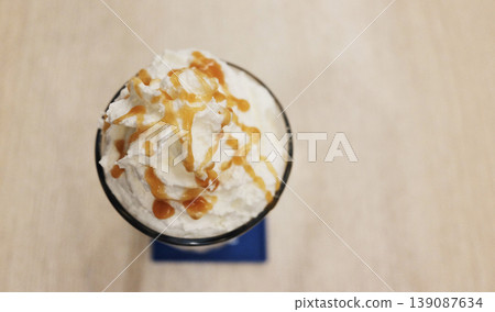 Iced latte coffee with whipped cream topped with caramel on a table in a traditional Thai cafe shop. Top view with copy space 139087634