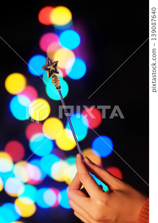 Close up woman hand holding star shaped wand in light bokeh on Celebrate Christmas background. Festive elegant abstract background Close up woman hand holding star shaped wand in light bokeh on Celebrate Christmas background. Festive elegant abstract background 139087640