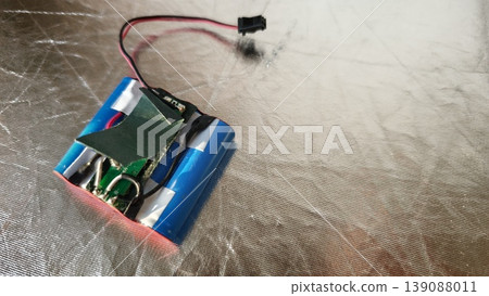 Battery pack with circuit board and wires on a silver surface Battery pack with circuit board and wires on a silver surface 139088011