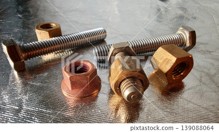 Different types of metal bolts and nuts on a shiny surface in a workshop Different types of metal bolts and nuts on a shiny surface in a workshop 139088064
