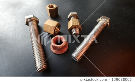 Assorted metal bolts and nuts on a dark surface showing different sizes and shapes Assorted metal bolts and nuts on a dark surface showing different sizes and shapes 139088065