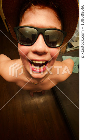 Young person smiling with sunglasses and a hat indoors in casual setting Young person smiling with sunglasses and a hat indoors in casual setting 139088066