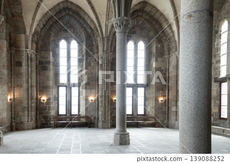 Interior gothic hall with tall arched windows columns and natural light illuminating historic architecture Interior gothic hall with tall arched windows columns and natural light illuminating historic architecture 139088252