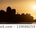 Rock formations silhouette with couple standing during sunset creating scenic coastal dramatic landscape view 139088259