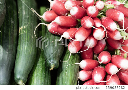 Close up fresh cucumbers and red radishes stacked together showing vibrant healthy organic vegetables Close up fresh cucumbers and red radishes stacked together showing vibrant healthy organic vegetables 139088282